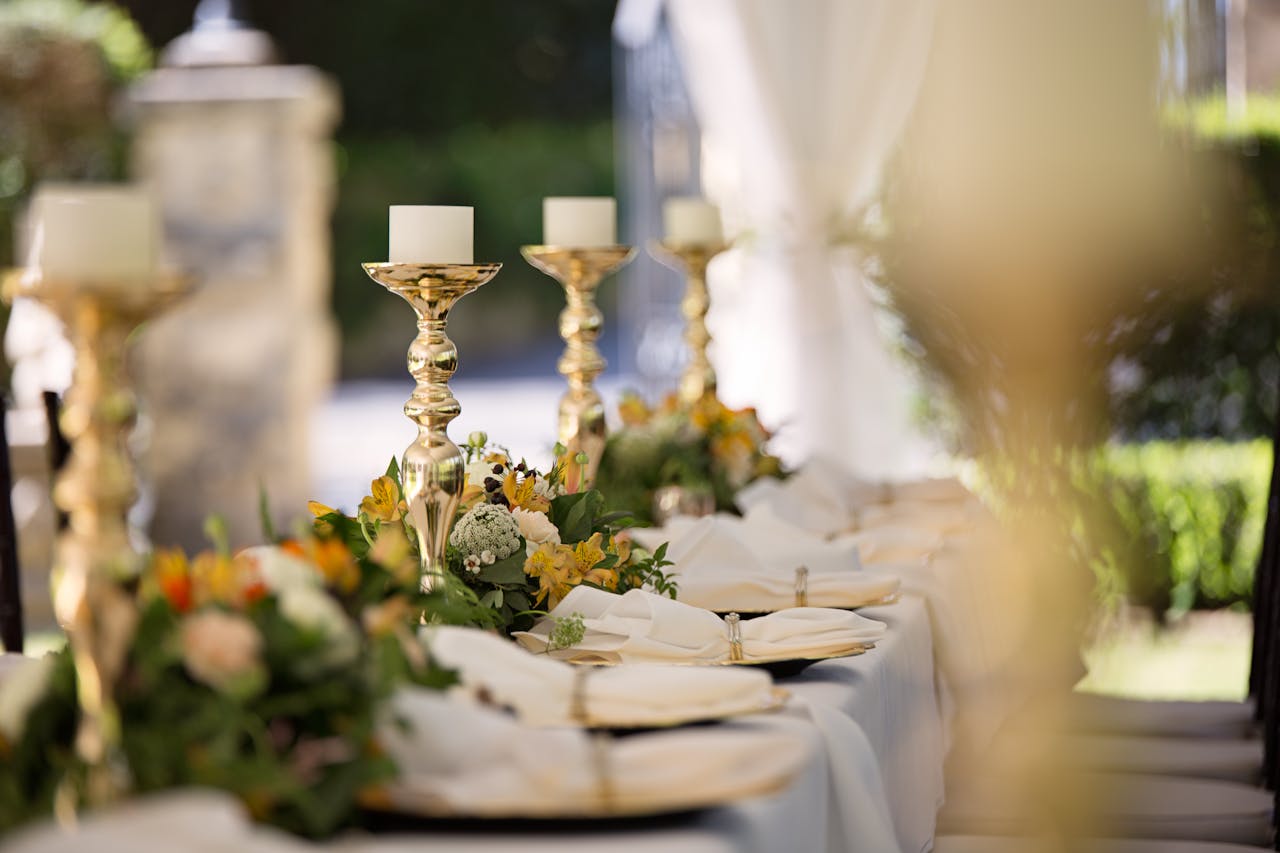 about-us Luxurious outdoor wedding table setting with flowers and candlesticks.